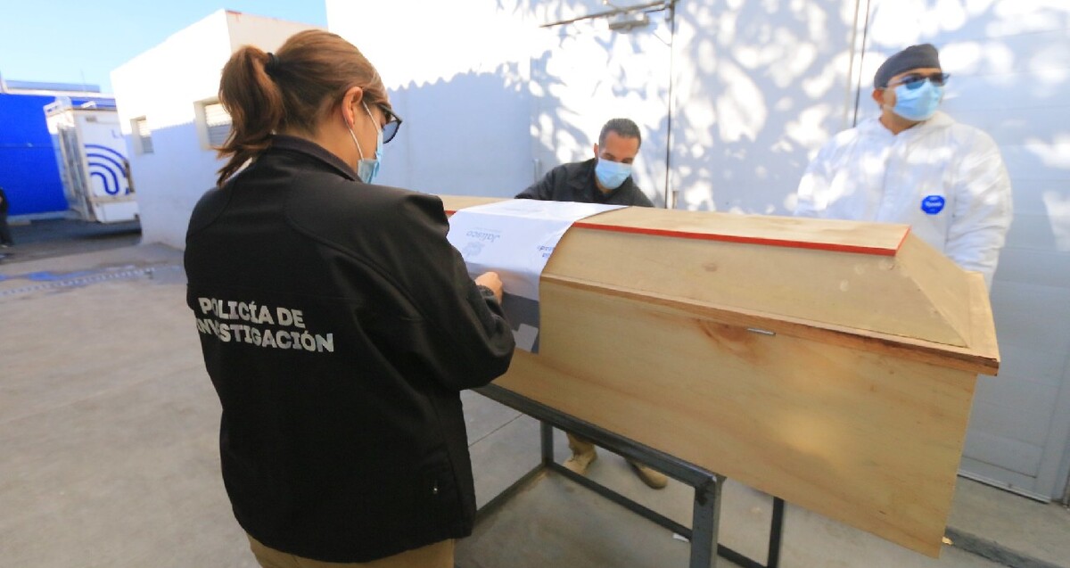 Trabajadora de la Policía de Investigación con miembros del IJCF colocando un sello del Gobierno de Jalisco a un féretro de madera