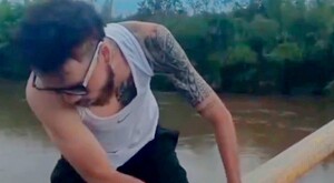 Ángel Montoya volteando a ver hacia abajo mientras está sujetado de un puente a la orilla del río Cauca