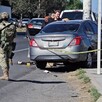 Militar del Ejército al lado de un Nissan Versa color gris acordonado por una cinta policiaca con personas alrededor y autos transitando al lado