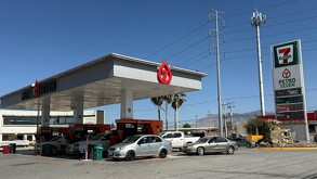 Se observa una gasolinera con autos estacionados, hay un número 7.
