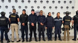 Cuatro hombre y una mujer miembros de la Guardia Civil de Morelia con los ojos censurados y en medio de policías de Michoacán