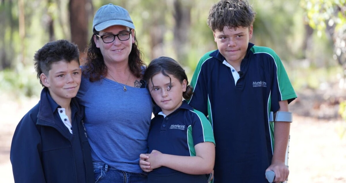 Madre de familia identificada como Joanne Appelbee con su hijo Beau a la izquierda y sus hijos Grace y Austin a la derecha con plantas y árboles en el fondo