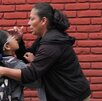 Una mujer da la bendición a su hija antes de dejarla en la escuela.