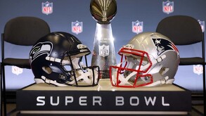 El Trofeo Vince Lombardi se encuentra entre los cascos de los Seattle Seahawks y los New England Patriots sobre un podio con la frase 