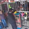 Asaltante recibiendo dinero de una cajera al interior de una papelería con una madre y su hija observando a la izquierda