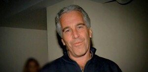 Jeffrey Epstein viendo a cámara mientras sonríe y viste un suéter color azul con una mujer desenfocada en el fondo
