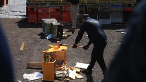 Un oficial de la Guardia Civil destruye una máquina de juegos ilegal con un mazo en un espacio al aire libre, rodeado de otras máquinas incautadas.