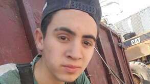 Joven con gorra y playera verde mirando a la cámara