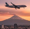 un avión volando sobre la ciudad de puebla con el volcán popocatépetl de fondo