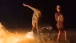 Llamas alcanzando a un joven alrededor de una fogata