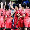 Jugadores de la Selección de Corea del Sur saludándose dentro de una cancha de futbol.