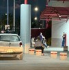 Se observa una camioneta blanca estacionada y al fondo unas personas sentadas.