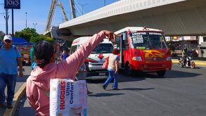 Una mujer hace la parada a un camión del transporte público en Puebla.