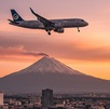 un avión volando sobre la ciudad de puebla con el volcán popocatépetl de fondo