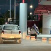 Se observa una camioneta blanca estacionada y al fondo unas personas sentadas.