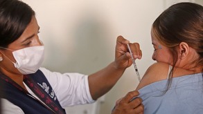 Una mujer hace un gesto de dolor mientras es vacunada contra el sarampión.