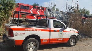 Camioneta de Protección Civil del Estado de Colima con un tren de la empresa Ferromex circulando a un costado