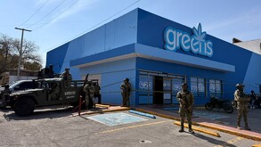 Se observan a unos militares portando su uniforme, afuera d enegocio en color azul que dice greens 4:20.