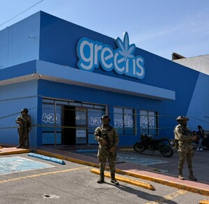 Se observan a unos militares portando su uniforme, afuera d enegocio en color azul que dice greens 4:20.