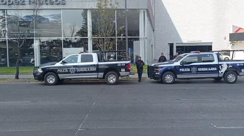 Dos patrullas y varios oficiales de la Policía Municipal de Guadalajara al exterior de una agencia de autos de lujo en la Avenida López Mateos
