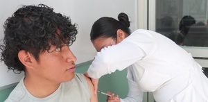 una enfermera aplica una vacuna a un joven en el brazo