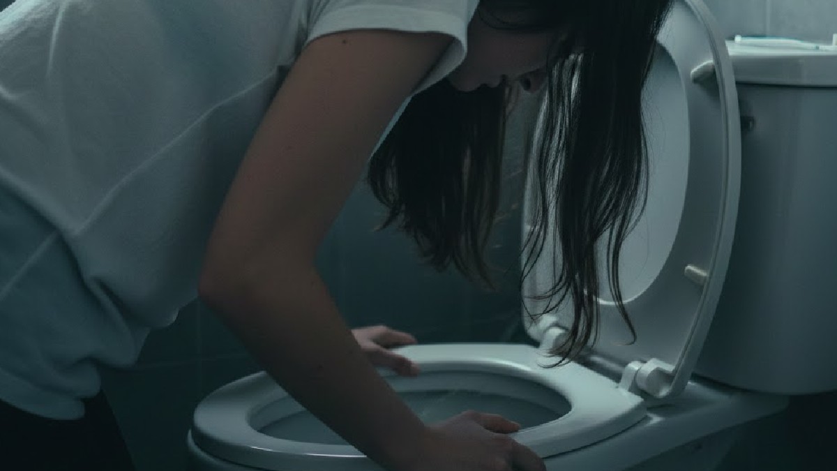 Joven agachada en un inodoro en color gris