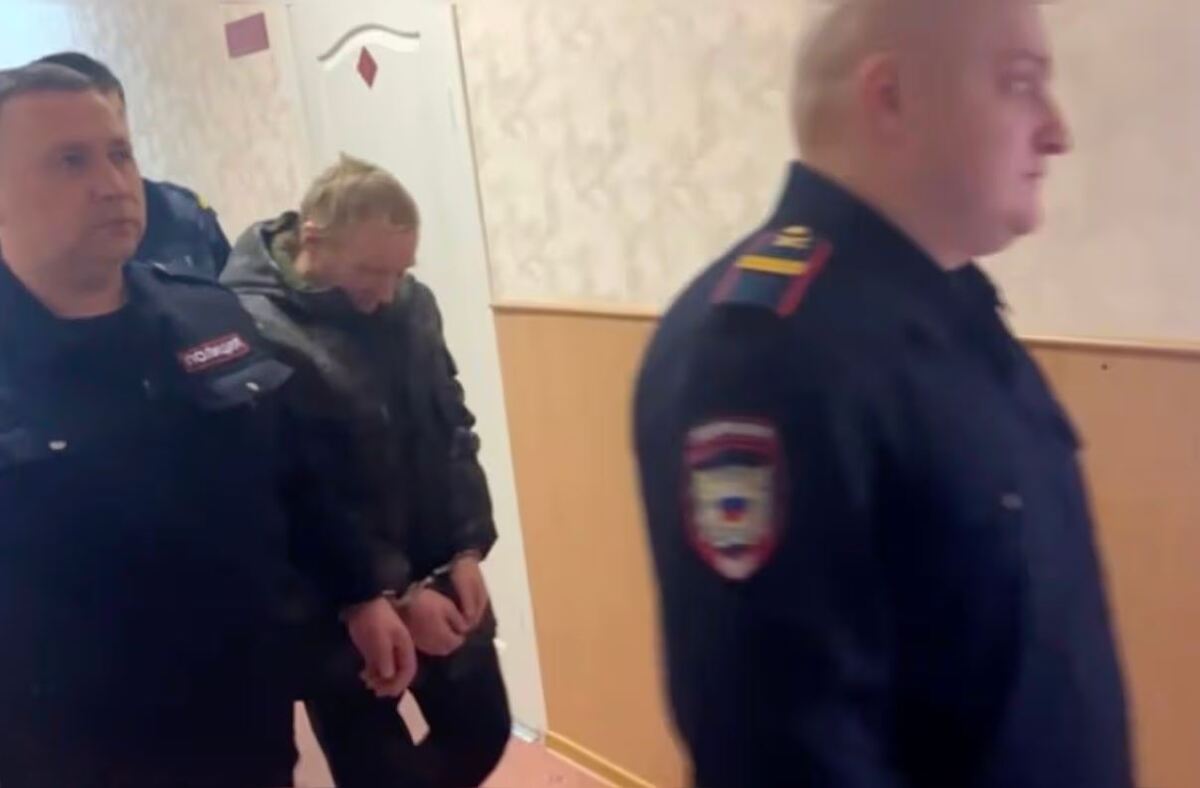 Tres policías de Rusia llevándose a un granjero que camina con la cabeza agachada y con esposas en las manos