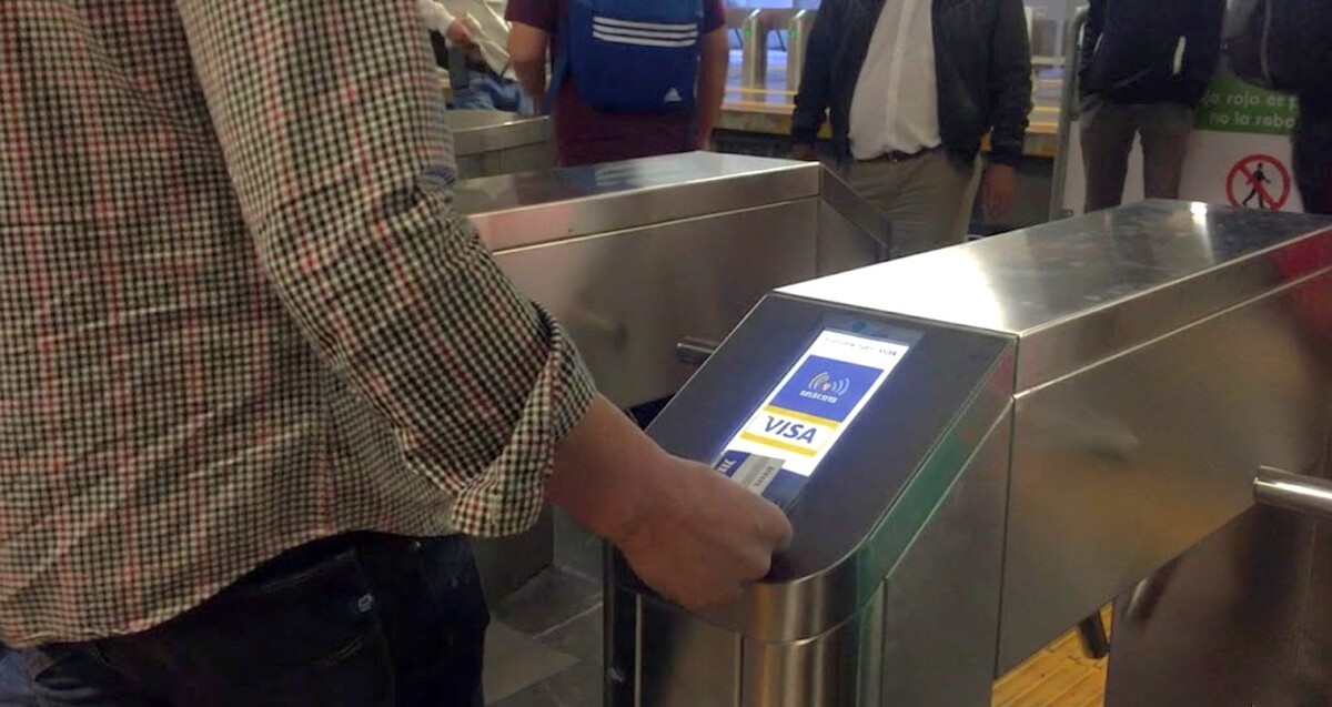 Hombre pagando con una tarjeta Visa el pasaje de una estación del Tren Ligero en Guadalajara, Jalisco