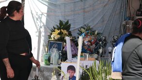 Mujer vestida de negro asiste a un funeral donde cuelga la foto de un menor de edad.