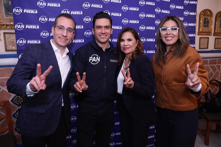 Dos hombres y dos mujeres hacen una señal con la mano mientras posan para una foto.