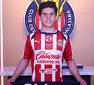 Jugador Jonathan Pérez vistiendo la jersey del equipo de las Chivas del Guadalajara parado delante del escudo del equipo