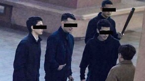 Se observa a varios chicos, algunos vistiendo ropa negra y hay otro con chamarra café; uno de ellos trae un bate en la mano.