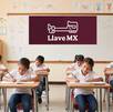 Un grupo de niños en un salón de clases mientras realizan apuntes, y en el fondo un pizarrón en el que esta dibujado el logo de Llave MX