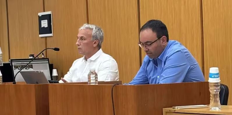 Mauricio Javier Atencio Krause con camisa azul sentado al lado de su abogado con camisa blanca al interior de la sala 5 de Tribunales de General Roca