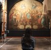 una mujer sentada en una banca observando una pintura en un museo de puebla