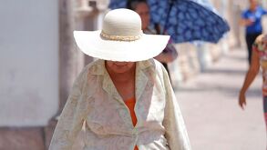 Mujer con sombrero caminando bajo el sol.