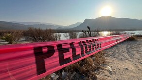 Se observa una cinta de precaución color roja y un lago al fondo.