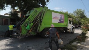 Se observa un camión de basura y dos hombres a lado de éste.