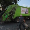 Se observa un camión de basura y dos hombres a lado de éste.