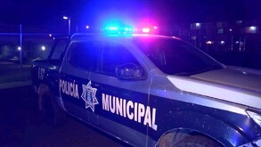 Patrulla de la Policía Municipal de El Salto estacionada delante de un enrejado y con la sirena encendida durante la noche