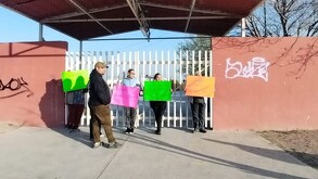 Se observa a varias personas, entre mujeres y hombres, algunos traen cartulinas en las manos.