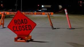 Señal de tránsito color roja indicando que la calle está cerrada delante de una vaya de seguridad en medio de una calle que dirige hacia una escuela