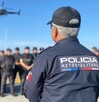 Oficial de la Policía de Jalisco al lado de un elemento de la Policía Metropolitana parados delante de policías del estado con un helicóptero sobrevolando