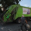 Se observa un camión de basura y dos hombres a lado de éste.