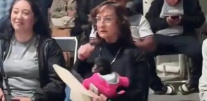 Regidora de Ocotlán, Silvia Iliana Villarruel Gutiérrez sentada y sosteniendo una cría de mono araña que viste un suéter rosa en medio de un evento público