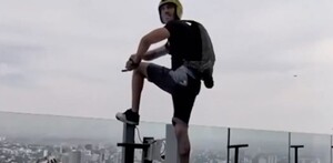 Hombre con un casco con una GoPro y una mochila con paracaídas posando un pie sobre el borde de un cristal del Hotel RIU en Guadalajara
