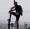 Hombre con un casco con una GoPro y una mochila con paracaídas posando un pie sobre el borde de un cristal del Hotel RIU en Guadalajara