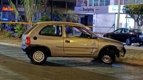 Automóvil Chevrolet Chevy color gris con la puerta del copiloto abollada detenido en medio de una calle de Guadalajara y detrás de una cinta policiaca