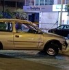 Automóvil Chevrolet Chevy color gris con la puerta del copiloto abollada detenido en medio de una calle de Guadalajara y detrás de una cinta policiaca