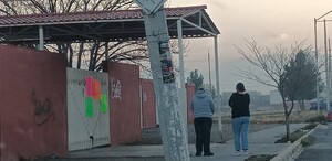 Se observa a dos mujeres paradas y enfrente de observan unas pancartas.